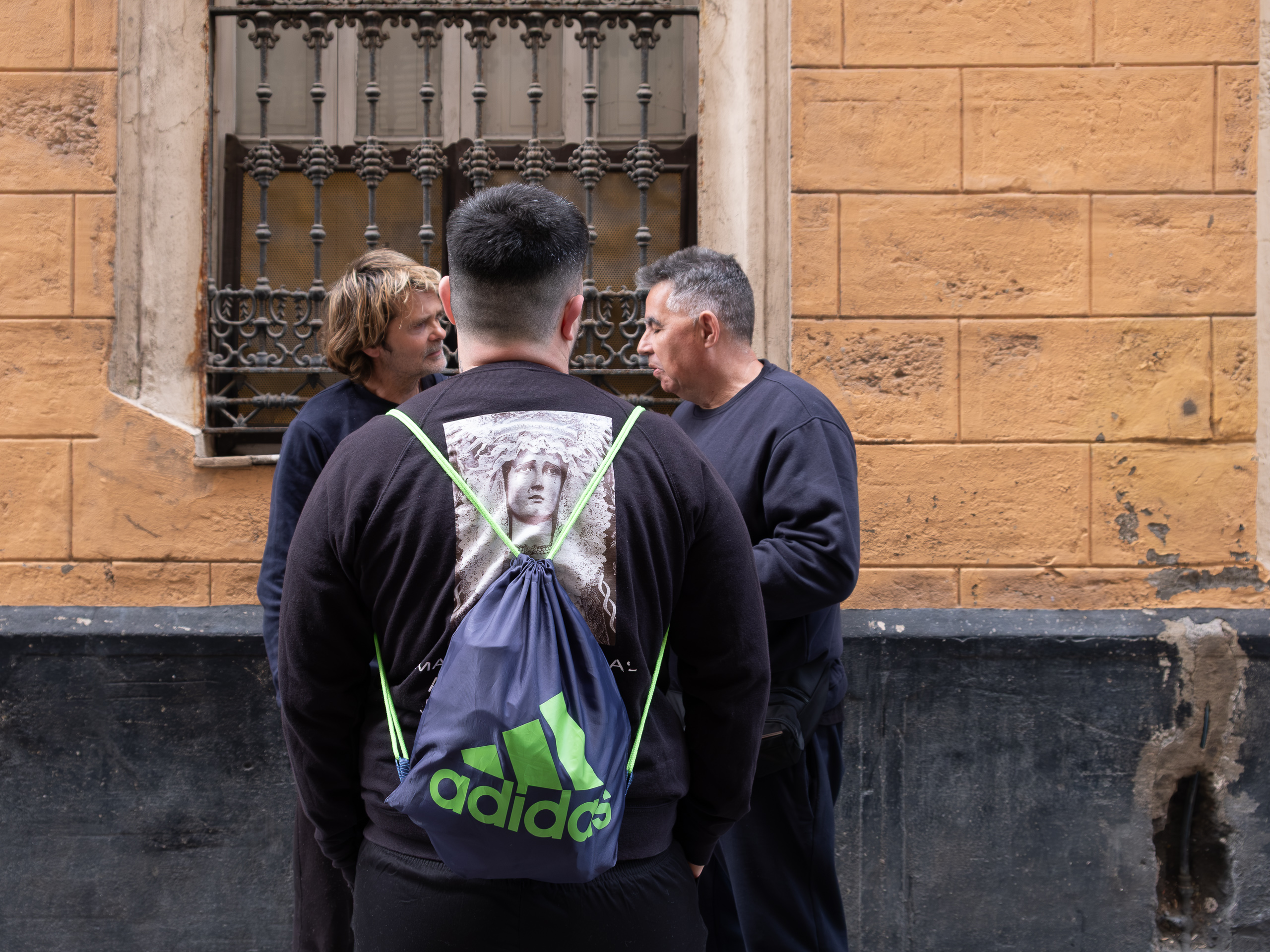 Gespräch in der Gasse – Rucksack mit Virgen-Aufdruck
